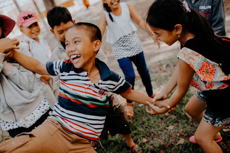 Kids playing outdoors. The child in the middle appears to be held up by other children.