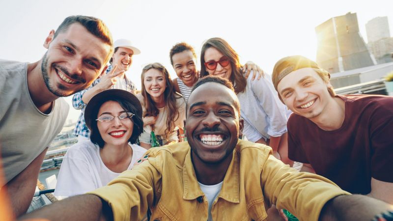 Group of friends smiling at the camera while taking a selfie together