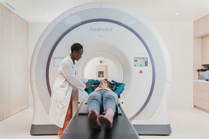 A doctor is talking to a woman entering an MRI machine.