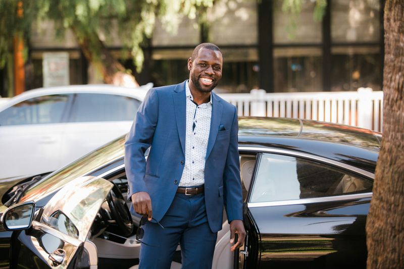 Confident business person walking out of car