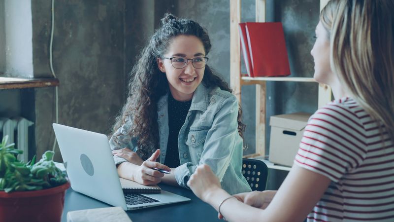 Two women talking over a laptop.