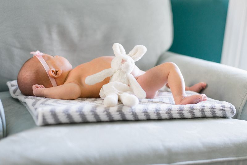 a baby rests on a blanket. There is a bunny stuffed animal next to her
