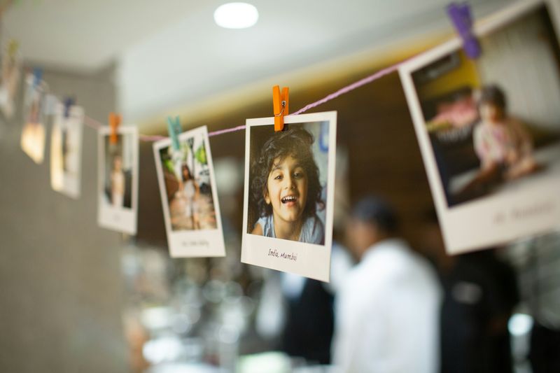 Polaroid pictures hung on a line with colourful small clothes pins. The pictures are of the same child at different ages.