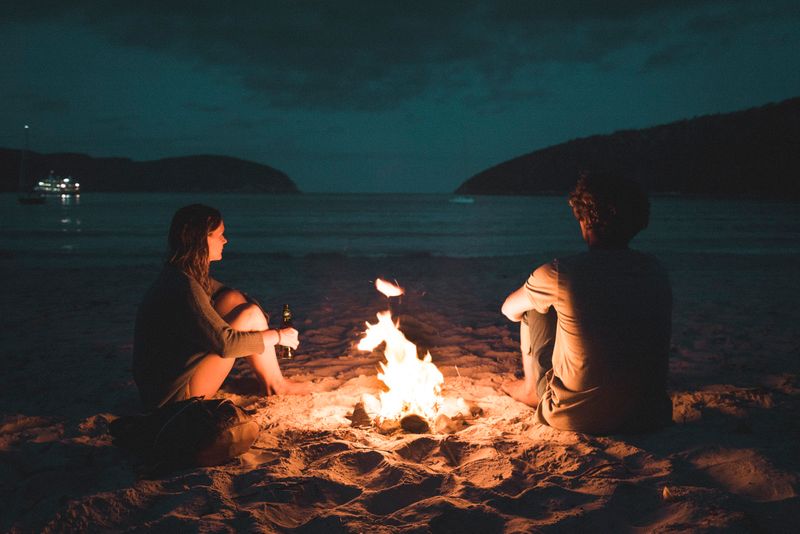 Two people on a beach in front of a camp fire