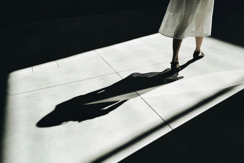 A shadow of a woman walking by is cast on the ground.