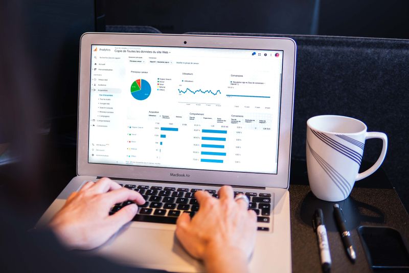 Laptop screen showing pie, bar, and line graphs with hands typing on keyboard.