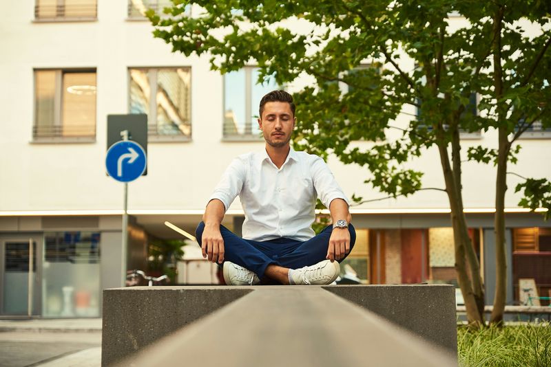 An office worker meditating outside of an office building.