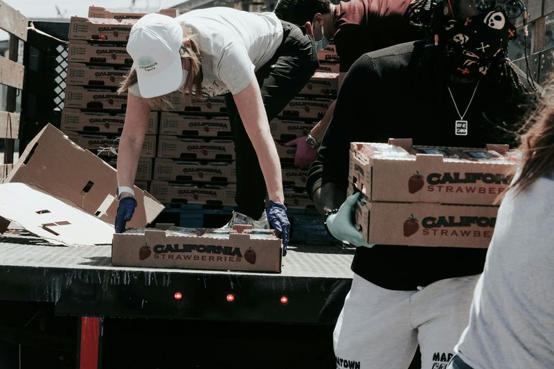 A group of volunteers unloading boxes of strawberries to distribute to their community.