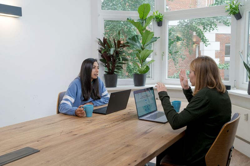 Two professionals sitting at a conference table, in the middle of an involved conversation. 