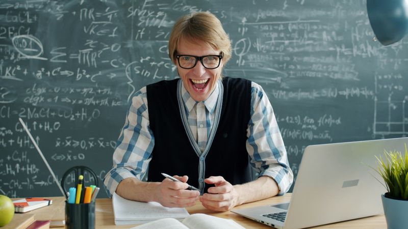 A motivated male teacher at his desk, smiling.