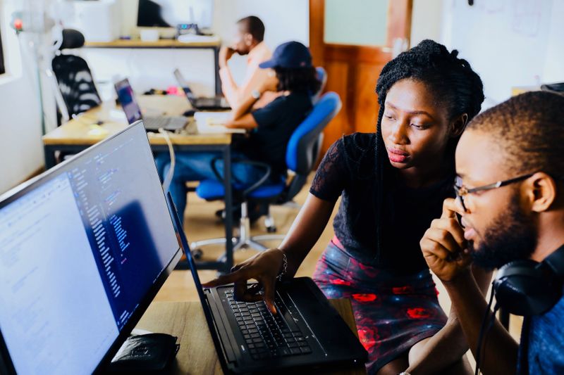 An image of a woman teaching a man how to do something on a computer.