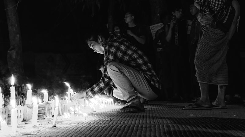 A person lighting a candle at a vigil