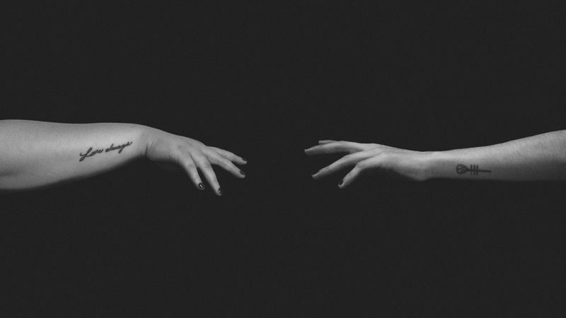 Two hands outstretched to each other but not touching. 