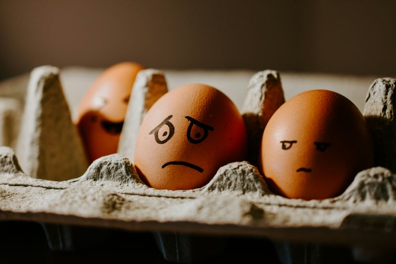 Three eggs in a carton with worried expressions drawn on their shells.