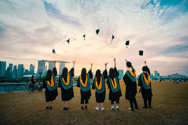 A group of friends throws their graduation caps together.
