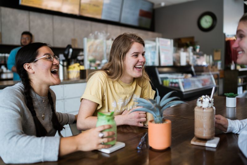 Three people laughing sitting around a table