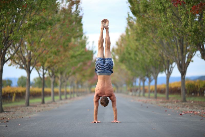 A person doing a handstand in the middle of the road.