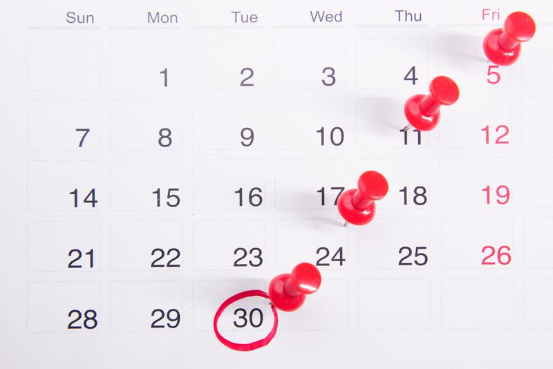 A calendar with red pushpins and the 30th circled.