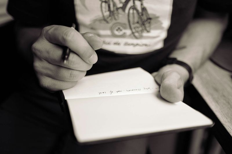 Close-up view of notepad with notes and hands holding a pen