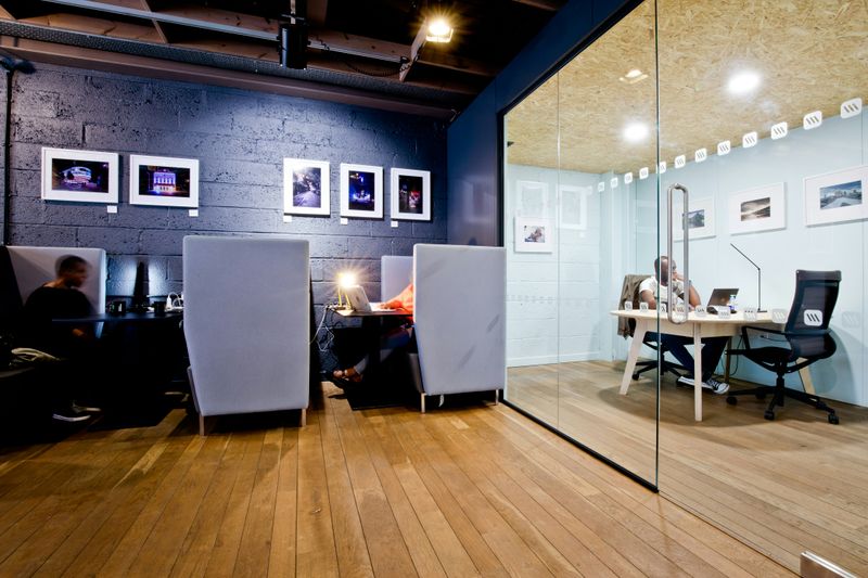 Closed layout office with people working in separate cubicles and one of them in a glass-walled office 