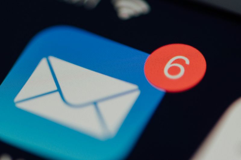 Closeup of email app icon with notification symbol on the corner indicating 