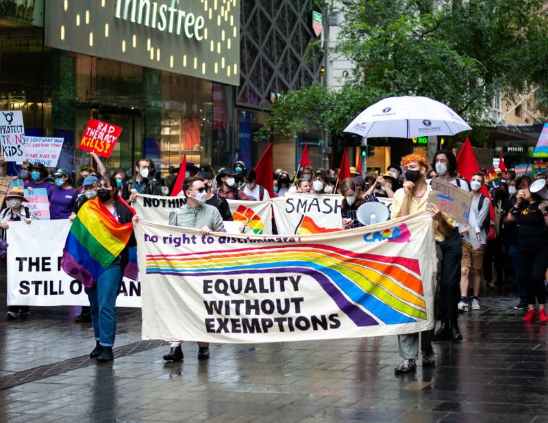 A protest march with people carrying a banner showing: Equality without exemptions