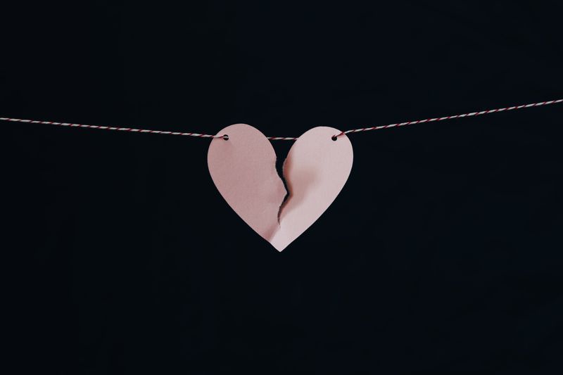 An image of a paper heart torn down the middle, and hanging from a string.
