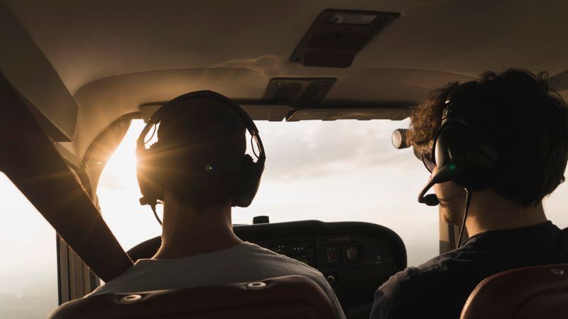 Pilots flying an airplane, view from behind the pilots out in front of the plane