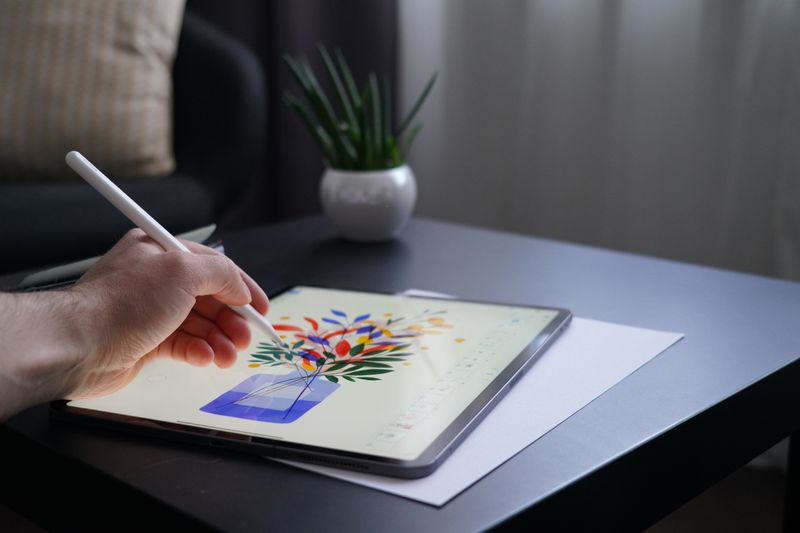 A person drawing a vase and flowers on a tablet.