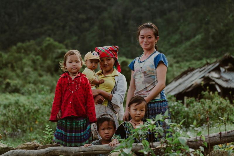 A group of Vietnamese village girls gather around a fallen tree.