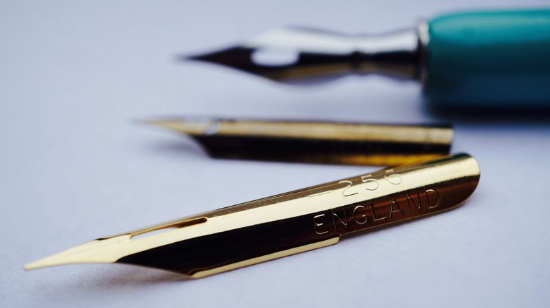 A close-up of metallic calligraphy nibs.