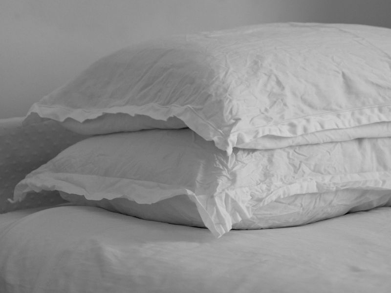 Two white pillows on a white bed.