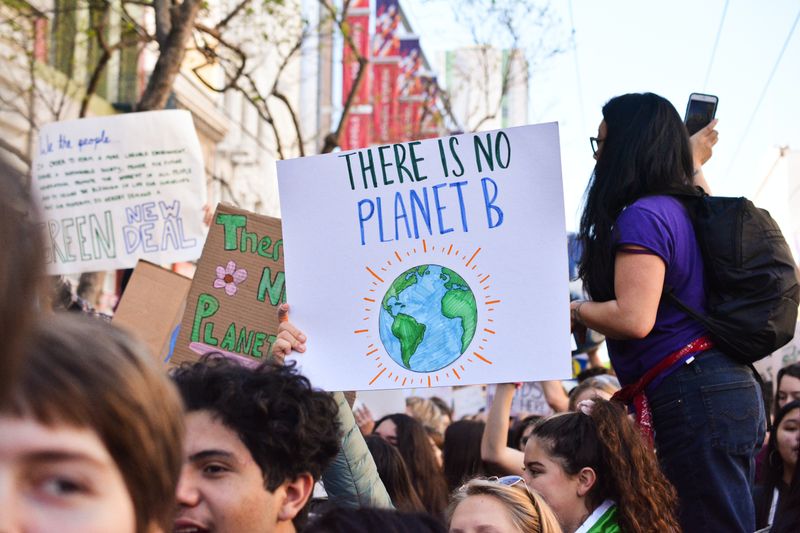 A protestor at a climate march holding a sign that says, 