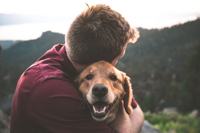 A person hugging a dog outdoors.