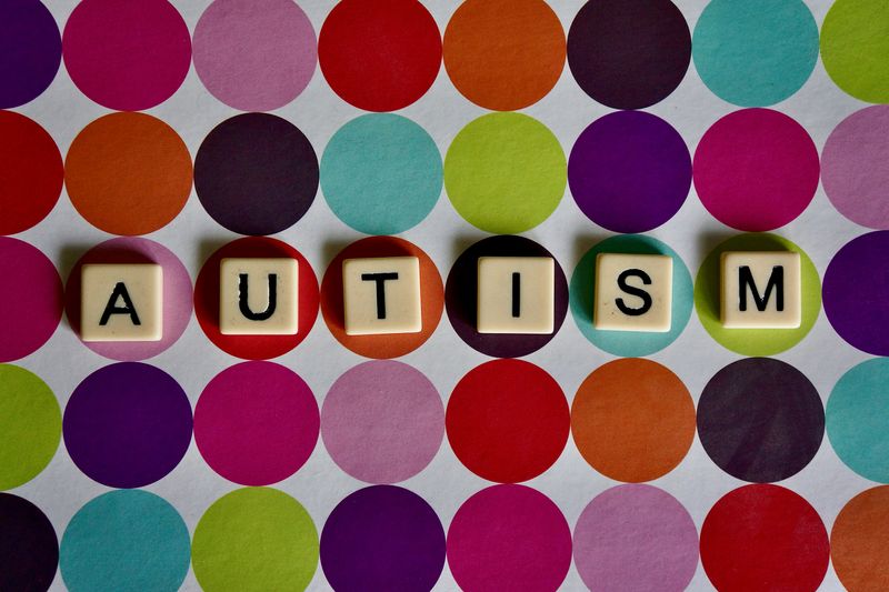 Scrabble letters that spell out 'autism' against a multi-colored background.