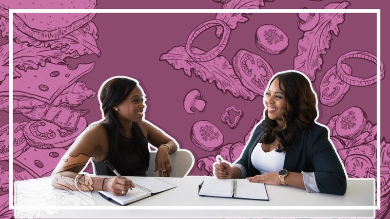 Two women in conversation and taking notes in their notebooks.