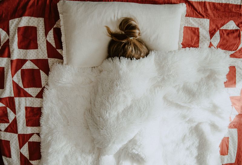 A woman in bed under her blanket