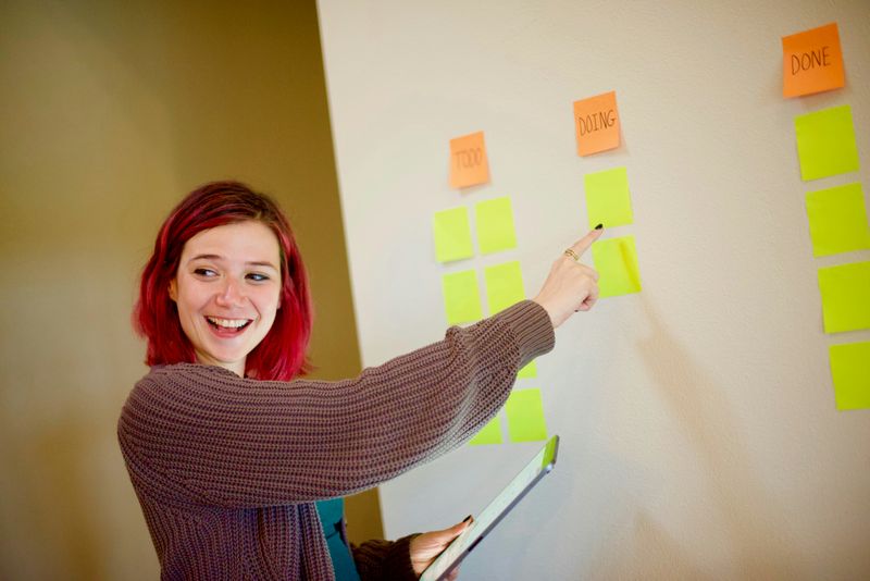 A teacher with sticky notes that say: To Do, Doing, Done.