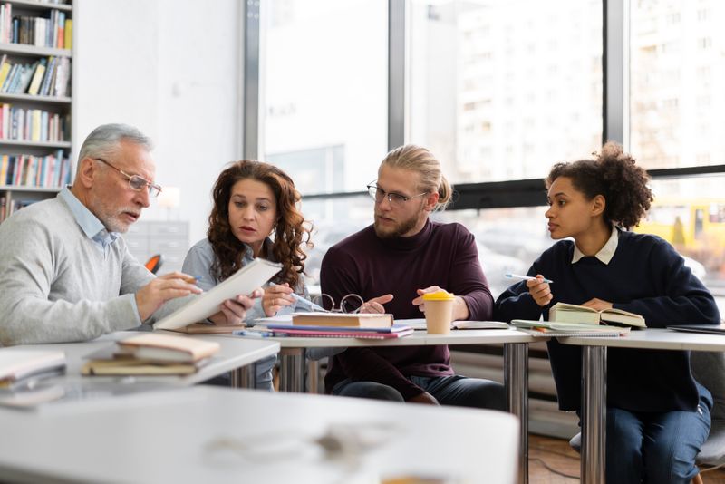 A group of college students meet with a professor in the library. Image by Freepik