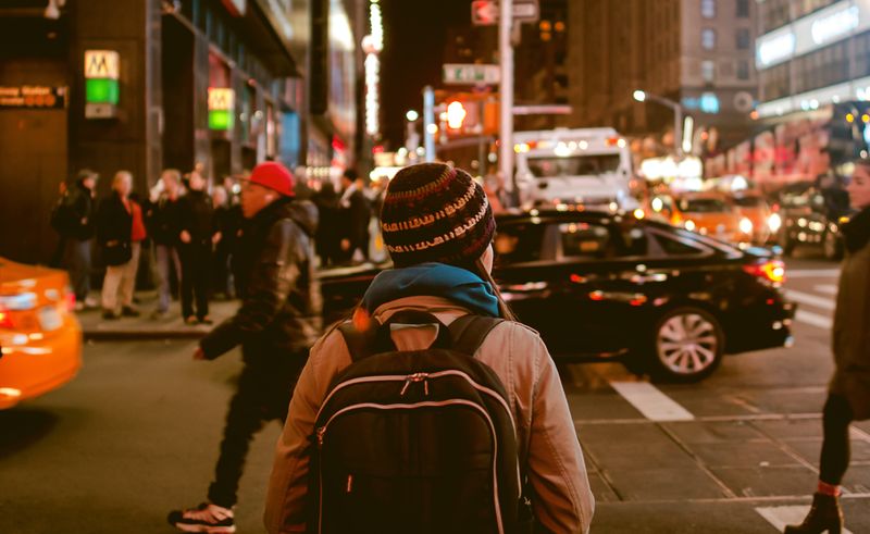 A woman crossing the street in a city at night.