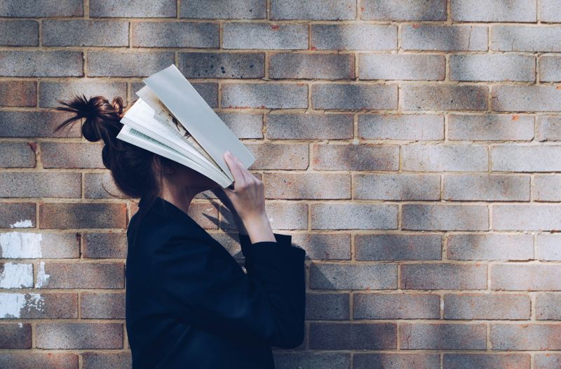 Woman is placing book on face in frustration 