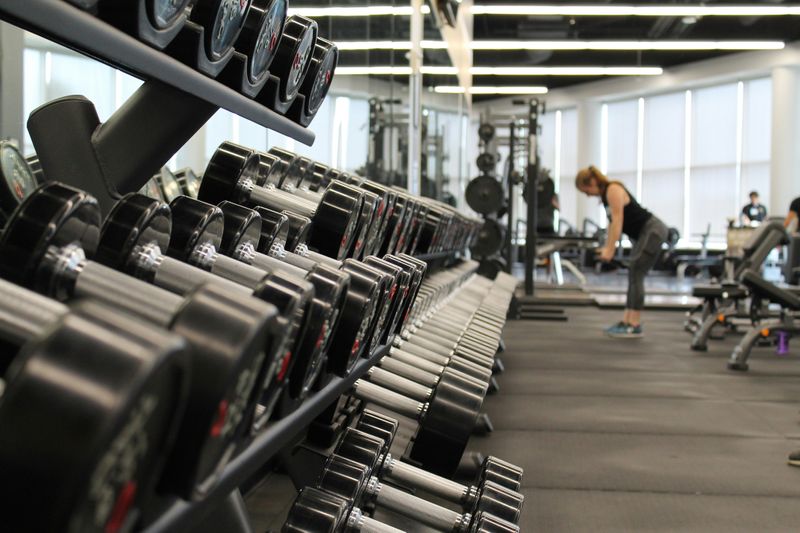 Rack of weights at a gym and people working out in the background