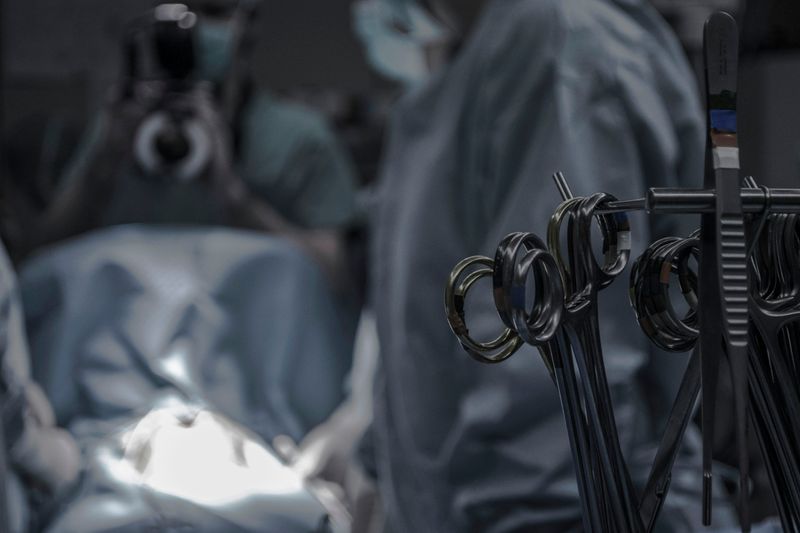 A patient in surgery with surgical instruments in the foreground.