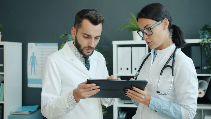 Two doctors look at a tablet in a doctor's office.