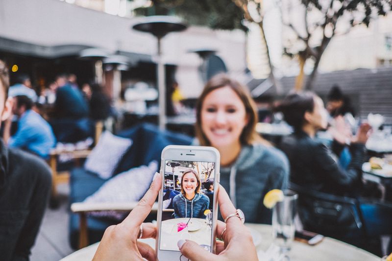 A person taking picture on iphone of a woman. 