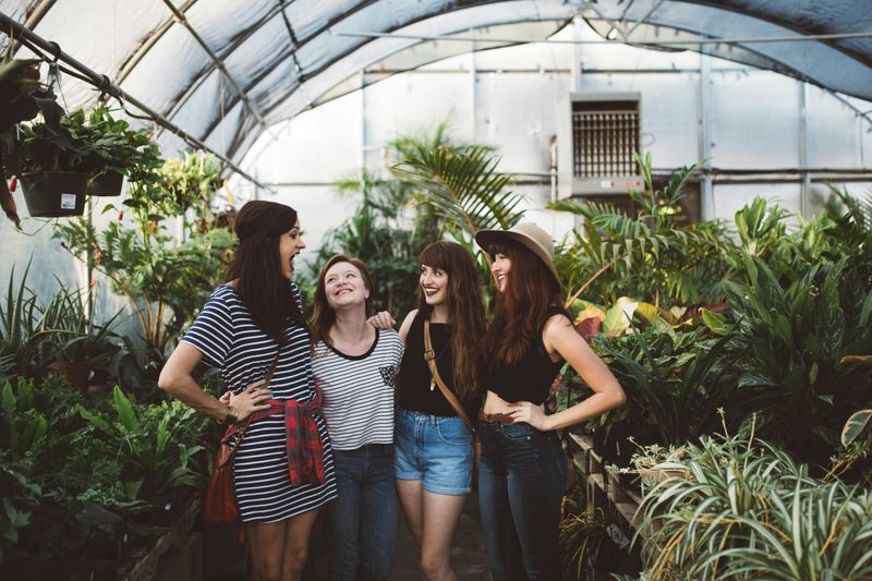 A woman with friends hanging out together in a greenhouse.