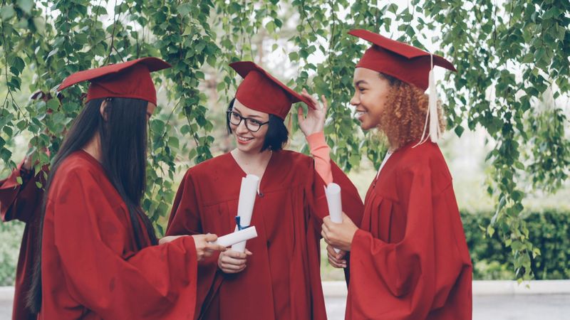 A group of female graduates talking outdoors on campus.