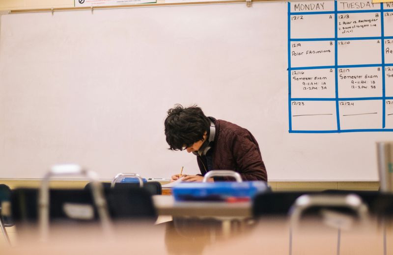 A student working at a desk in a classroom.