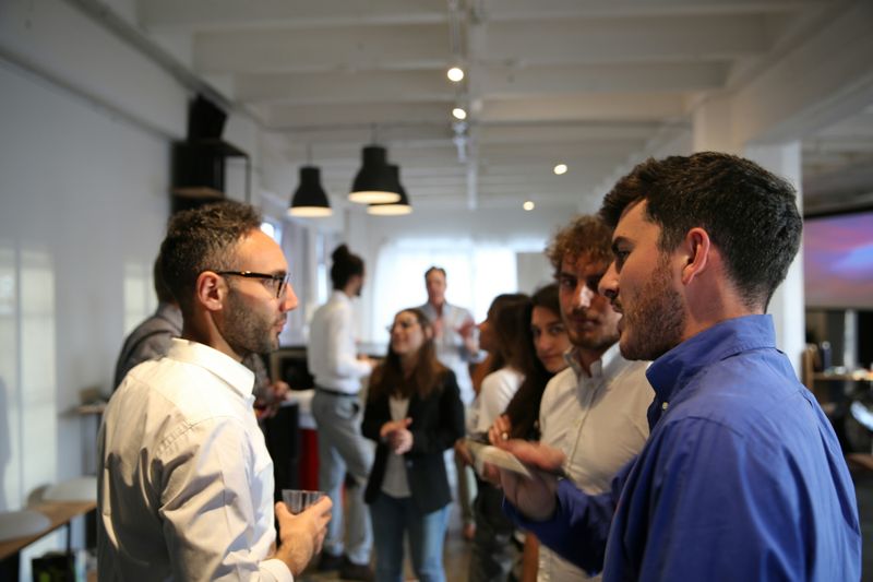 Young professionals are standing in an office spacing talking.