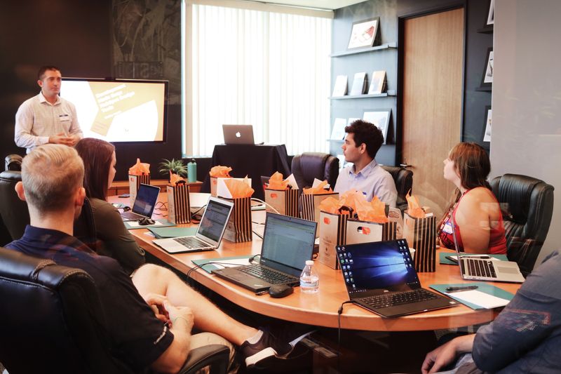 Man standing in front of a group of people who are seated at a conference table.